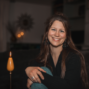 Woman sitting in a dark room with a candle lit beside her.